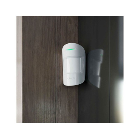 Ajax MotionProtect montado en pared interior detectando movimiento con luz LED verde